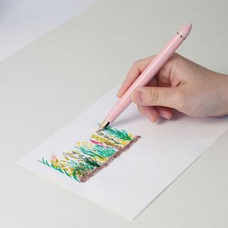 Pearl pink fountain pen held in hand writing colorful marks on paper
