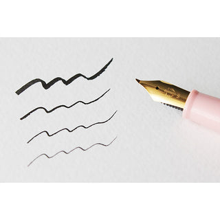 Pearl pink fountain pen nib writing on paper with curved ink strokes
