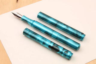 Teal anodized aluminum fountain pens with caps and nibs shown together