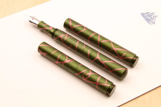Pocket 6 fountain pens, three green salmon splash anodized aluminum pens on paper