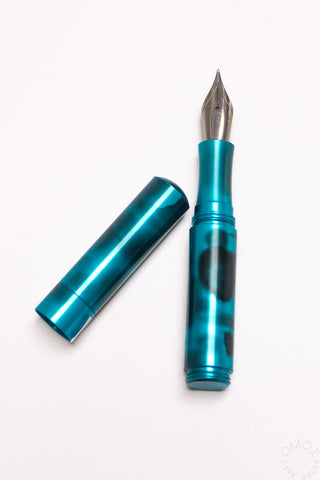 Teal anodized aluminum fountain pen with cap, showing the pointed nib