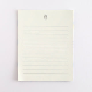 Blank note card with faint lines and small gray emblem at top