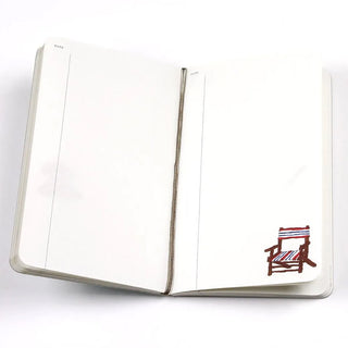 Open A6 diary with pen loop binding and small chair sticker on right page