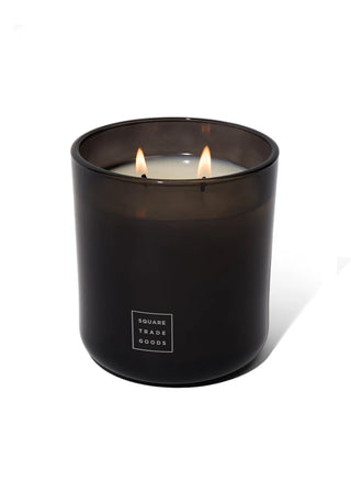 Square Trade Goods 16oz double-wick candle lit in dark glass jar with label