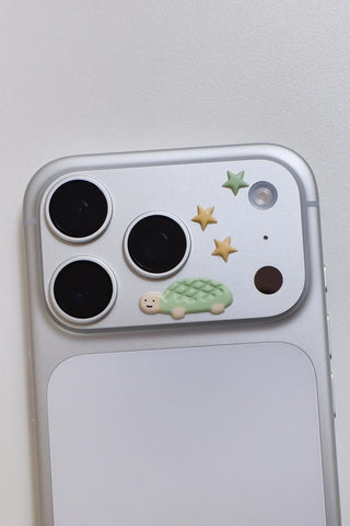 Puffy stickers on phone case: black circles, green turtle, and gold star shapes