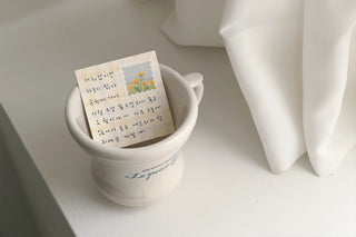 Green plaid sticky memo notes with handwritten card in white desk cup