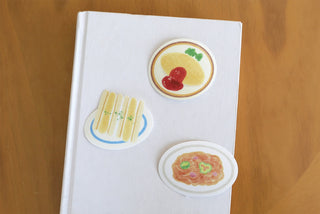 White notebook with three food stickers, including soup and grilled item shapes