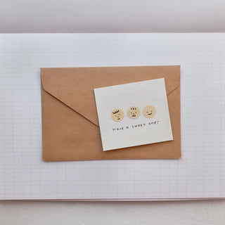 Sticker sheet card with two small round face stickers and text label, placed on envelope