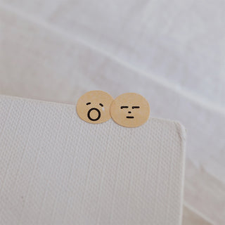 Two round emoji face stickers in beige tones with surprised and frowning expressions