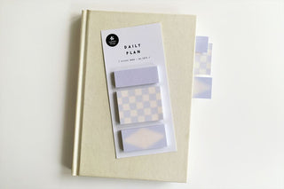 Pastel blue daily plan sticky memo set beside a kraft notebook with boxed notes
