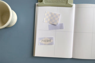 Open planner with checkered sticky note, lavender tab, and Friday memo