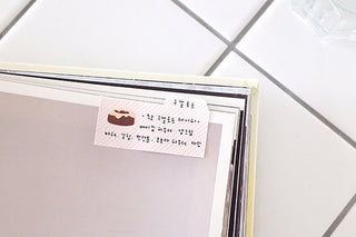 Tabbed sticky memo label attached to planner edge; close-up of the tab