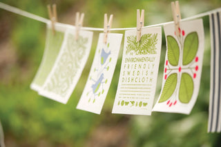 Set of floral Swedish dishcloths clipped on a line with green and pink leaf patterns