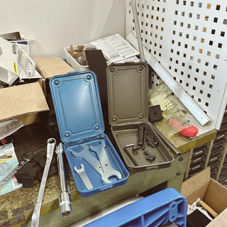 Open blue trunk-shaped toolbox with gray interior compartment and metal tools