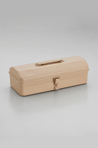 Beige metal tool box closed with front latch and handle on smooth surface