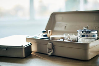 Beige tool box open with compartment dividers and small containers on tabletop