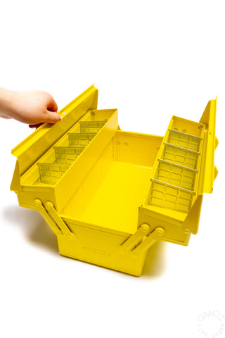 Hand holding open yellow cantilever toolbox with interior compartments and dividers