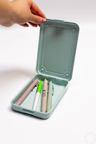 Light blue trunk-shaped toolbox open with stationery pens inside