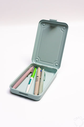 Light blue trunk-shaped toolbox open, pens and pencils in molded tray