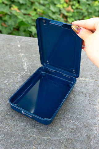 Navy trunk-shape metal toolbox with open lid held by hand