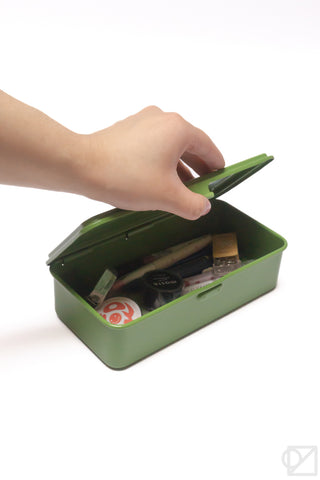 Green stackable storage box with lid open as a hand places items inside
