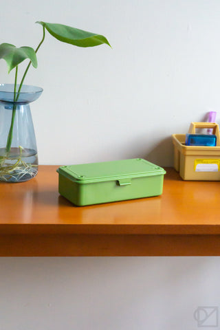 Green stackable storage box with lid closed and side latch on tabletop