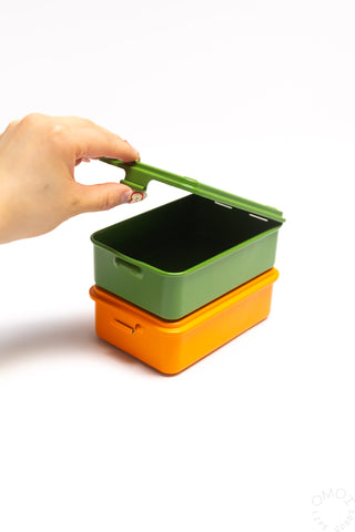 Trunk-shaped metal toolbox set with green lid lifted open over orange base