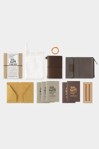 Brown leather card notebook set with refills and accessories, shown laid out.