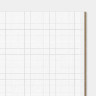 Grid paper close-up with light gray squares and a brown page edge
