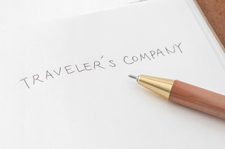 Wooden ballpoint pen with brass tip resting on paper
