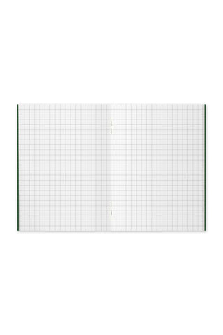 Open green-edged grid notebook spread with faint center seam