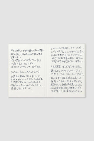 Passport-size notebook open to two handwritten note pages on cream paper