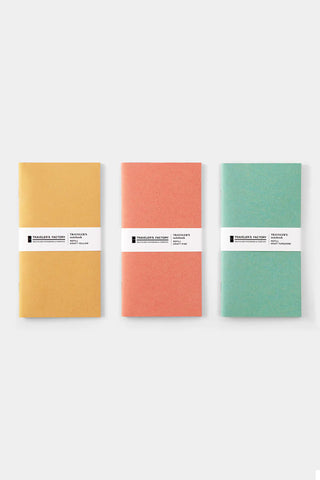 Three kraft notebook refills in yellow, pink, and turquoise with band labels