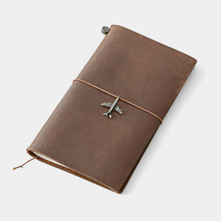 Brown leather notebook with pewter airplane charm centered on front.