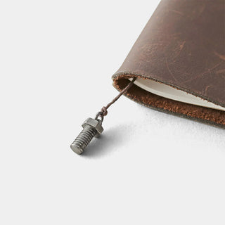 Pewter bolt charm on cord attached near brown notebook edge