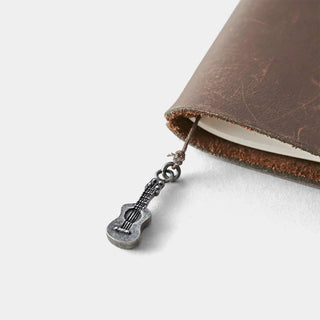 Pewter ukulele charm hanging from brown leather journal cover