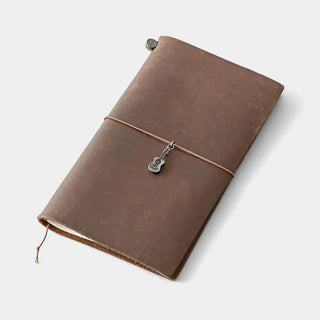 Pewter ukulele charm on brown leather journal with thin cord