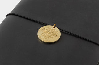 Gold 20th anniversary charm on a black cover with thin attachment cord