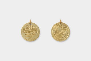 Two gold 20th anniversary Traveler's notebook charms with matching hanging holes