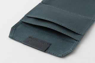 Dark card holder cover with stitched edges and front logo label