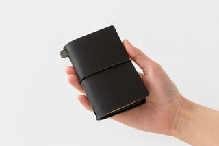 Black card-size notebook cover held in a hand
