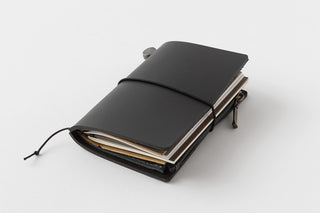 Black card-size notebook with elastic band and tied strap, stacked refills