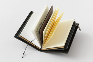Black notebook organizer open with cream and yellow pages, elastic closure