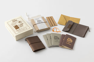 Brown leather card notebook set contents with small covers, papers, and labels.