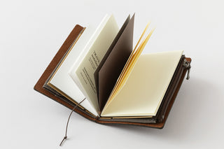 Brown leather card notebook open, cream inserts with yellow elastic and paper tabs.