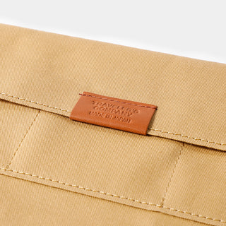 Beige cotton zipper case close-up of leather brand patch and edge stitching