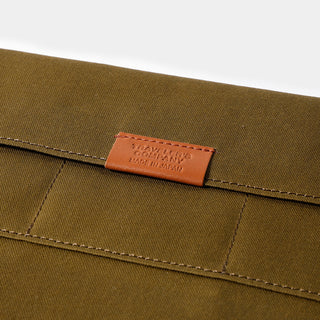 Olive cotton case with embossed orange leather-style brand patch and contrast stitching