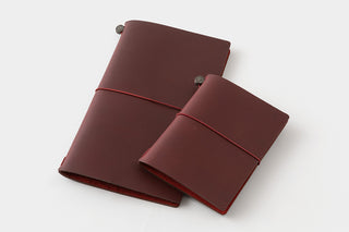 Two burgundy passport-size notebook covers with elastic strap and metal corner snap buttons
