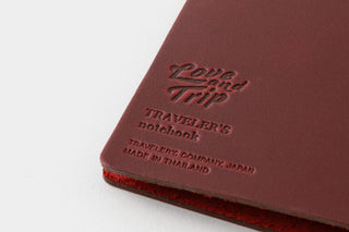 Red Traveler’s notebook cover with embossed “Love and Trip” title and brand text