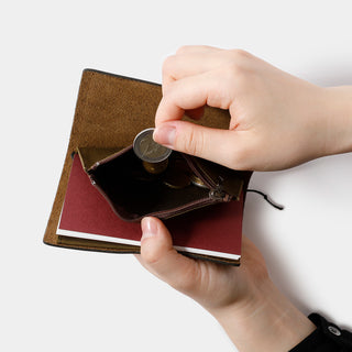 Hands inserting a passport into brown cotton zipper case, showing open document pocket